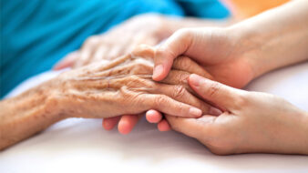 a nurse holding an elderly patient's hand