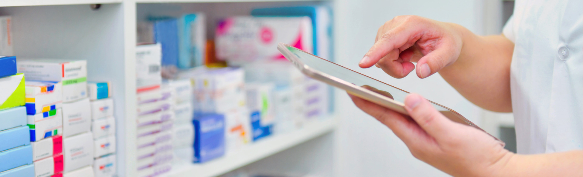 close up of a pharmacist holding a tablet device while checking medication stock