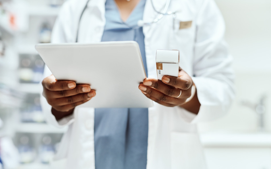 pharmacist looking at a medication and a tablet device