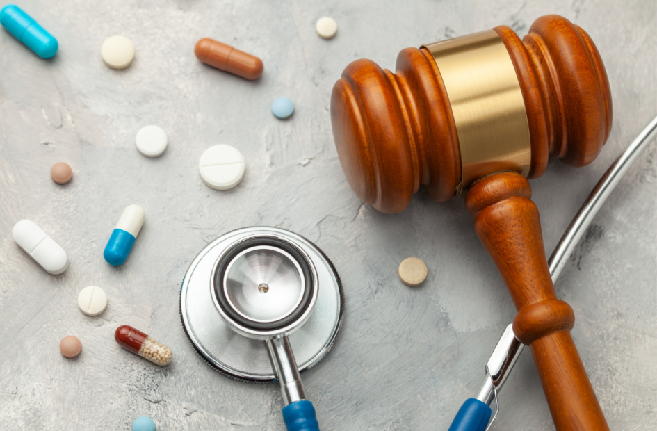 close up of judge gavel and stethoscope on tablet with pills surrounding