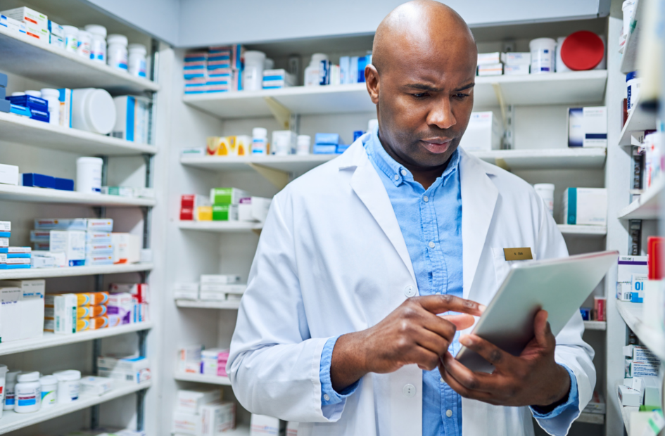 retail pharmacist working on a tablet device looking at legislative reports in the pharmacy stock room