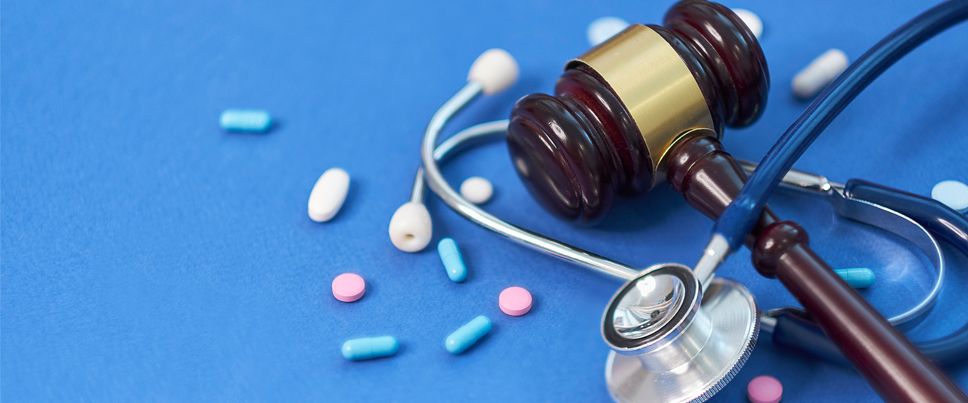 blue background with judge gavel and pills and stethoscope
