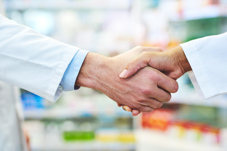 two pharmacists shaking hands in a pharmacy