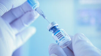 closeup of hands holding syringe and measles vaccine