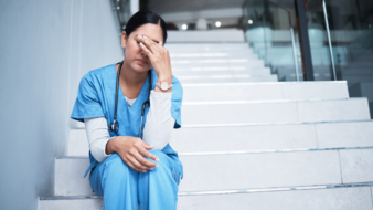 nurse sitting on a staircase looking stressed