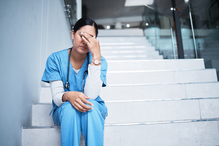 nurse sitting on a staircase looking stressed