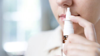 close up of a woman using nasal spray