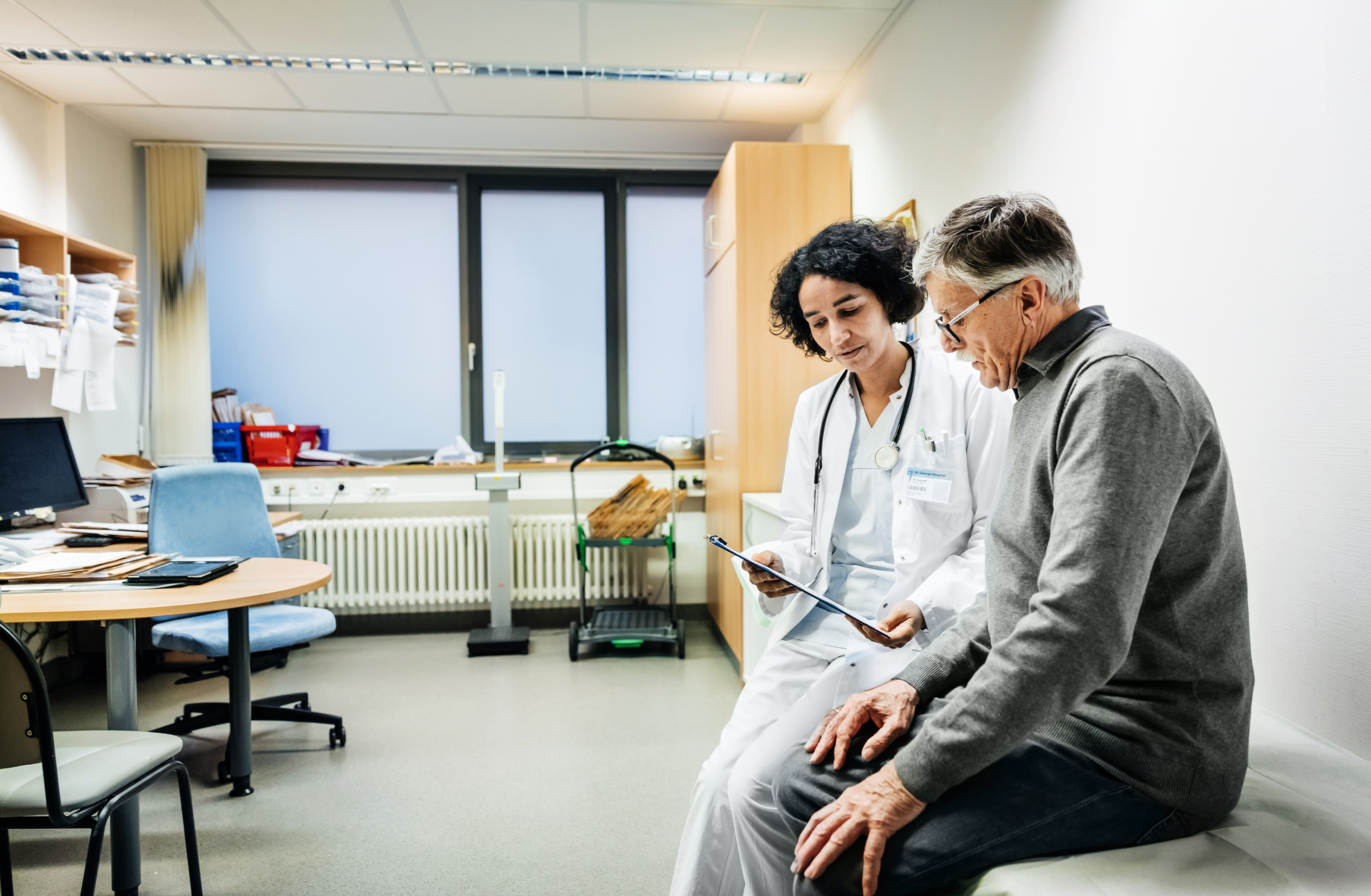 doctor sitting with patient looking at a tablet device together