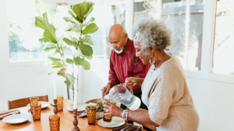two senior adults setting the dinner table