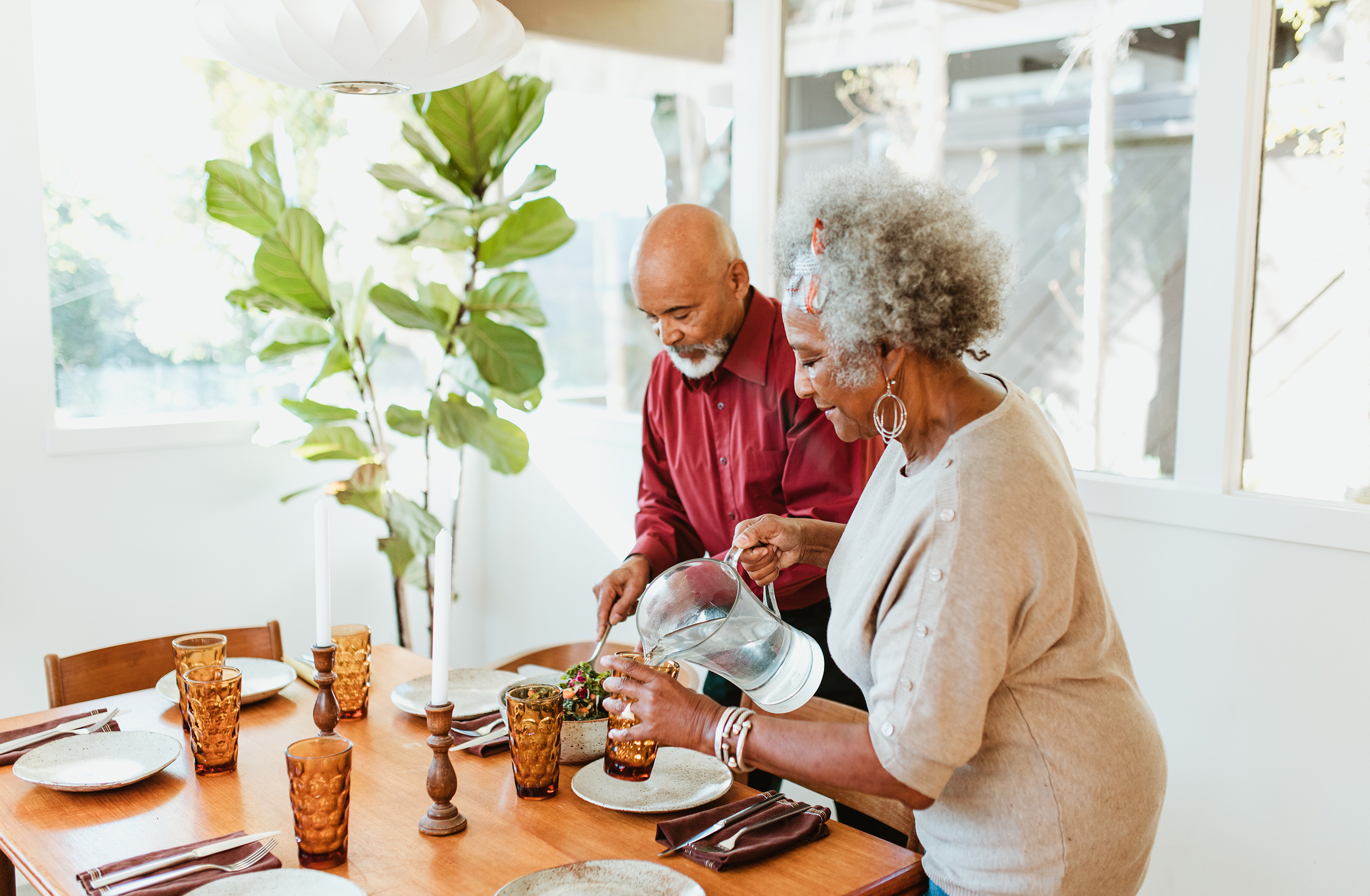 two senior adults setting the dinner table