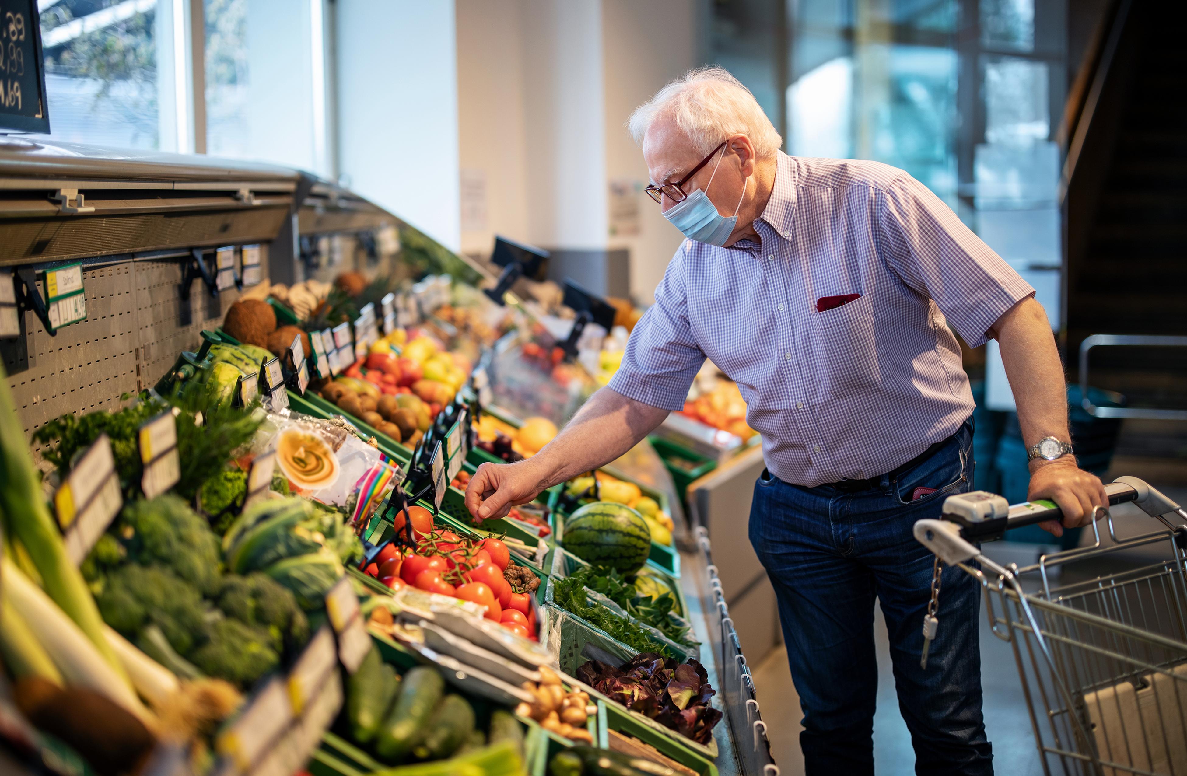 senior man picking fruit at a grocery store