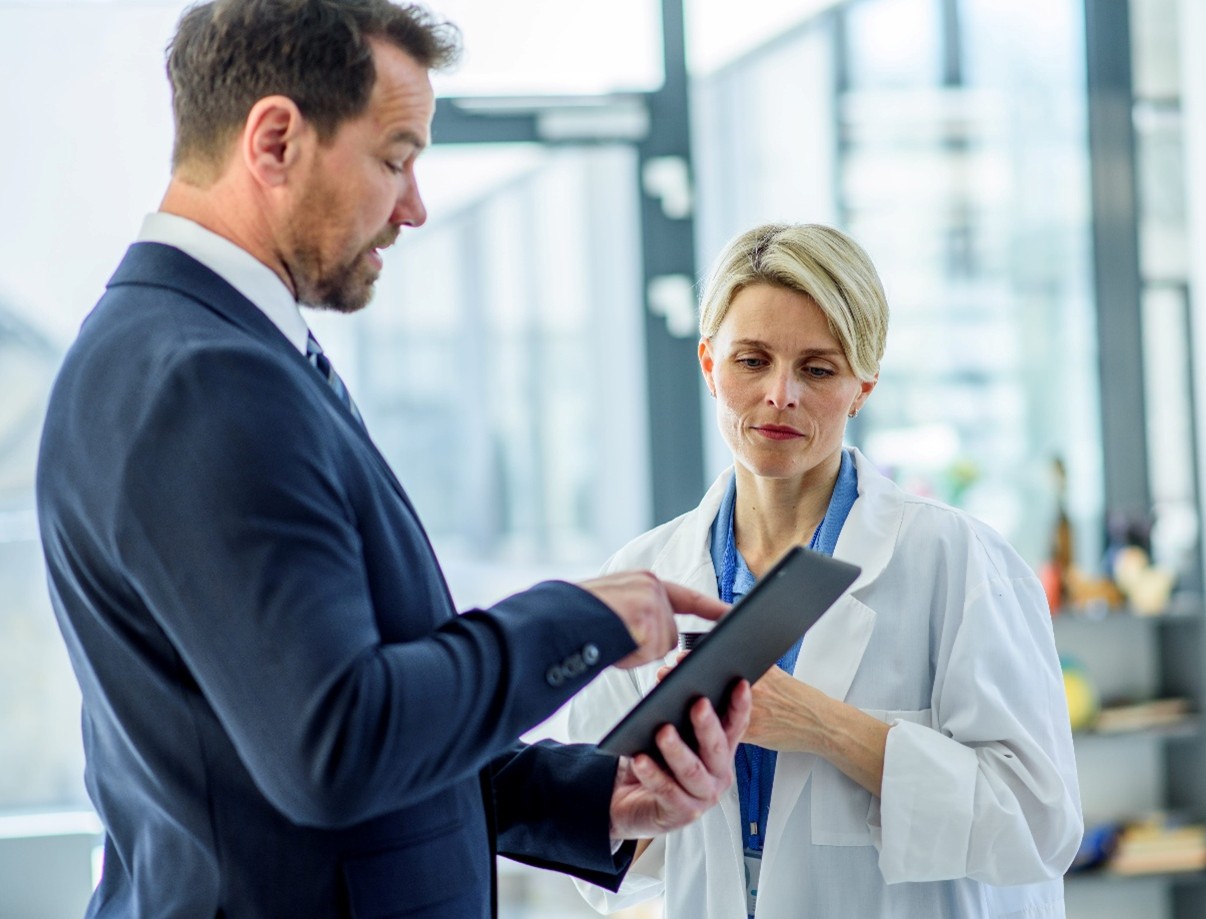 Woman in lab coat and man in suit discussing findings